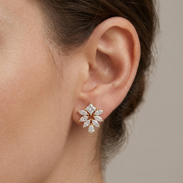 Model wearing a yellow gold sunburst cluster stud earring featuring a princess-cut diamond top, a fan of marquise diamonds, and a pear-cut diamond bottom, shown in its exact size on the earlobe.