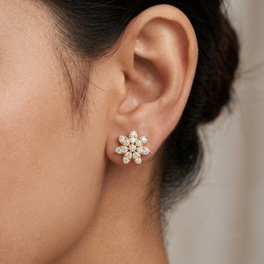 Model wearing a yellow gold floral bloom stud earring featuring eight diamond-paved marquise petals encircling a center round diamond, shown in its exact size on the earlobe.