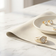Lab-grown diamond jewellery including ring, necklace and bracelet arranged with cleaning tools on ivory fabric in a luxury care concept.