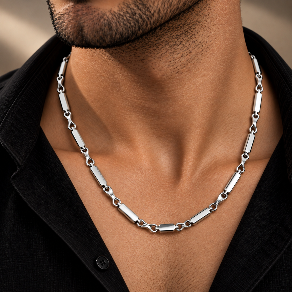 Men’s platinum chain featuring an alternating bar-and-link design displayed on a warm studio surface