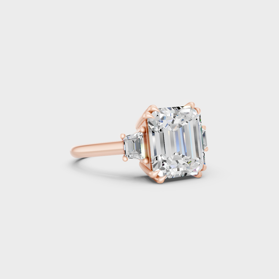 Stunning 4.28 Carat Emerald and Baguette-Cut Lab-Grown Diamond Three-Stone Ring in a 14K Rose Gold setting.