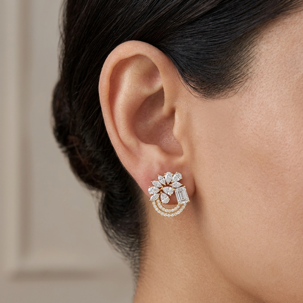 Model wearing a yellow gold swirl cluster stud earring featuring pear-cut and baguette diamonds anchored by double pavé diamond arcs, shown in its exact size on the earlobe.