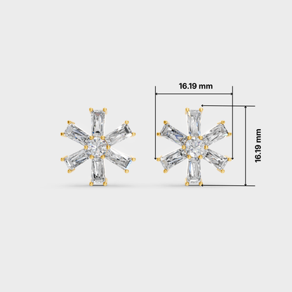 A pair of snowflake-shaped stud earrings with clear baguette and round-cut stones in a yellow gold setting, shown on a light gray background with dimension lines indicating a size of 16.19 mm.