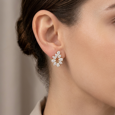 Model wearing a gold floral cluster stud earring set with marquise and pear-cut diamonds, shown close-up on the earlobe.